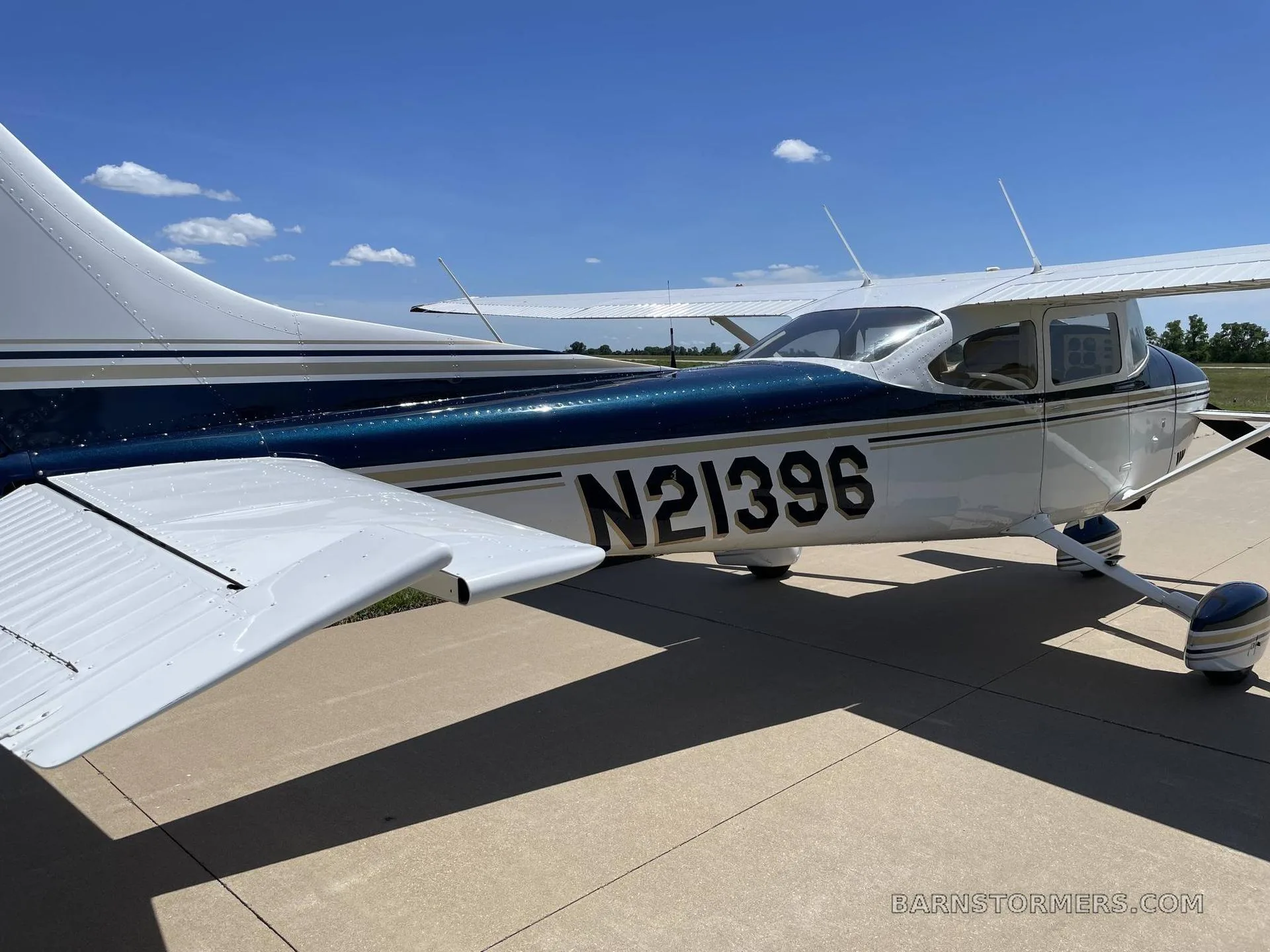 A white and dark blue Cessna 172 with registration N21396 parked on a tarmac under a clear blue sky.