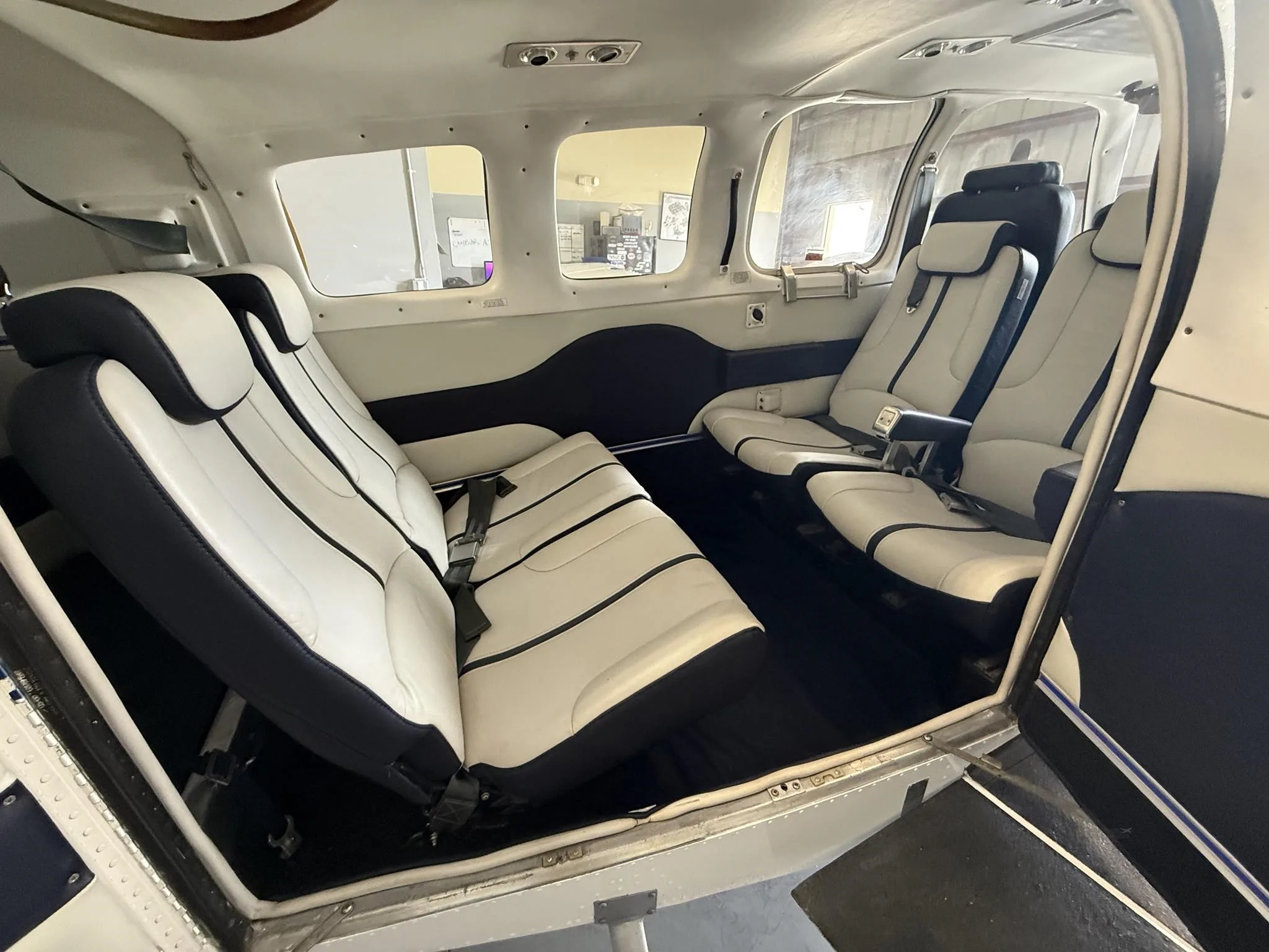 A wider view of the aircraft's interior cabin with white and blue leather seats and dark blue carpet.