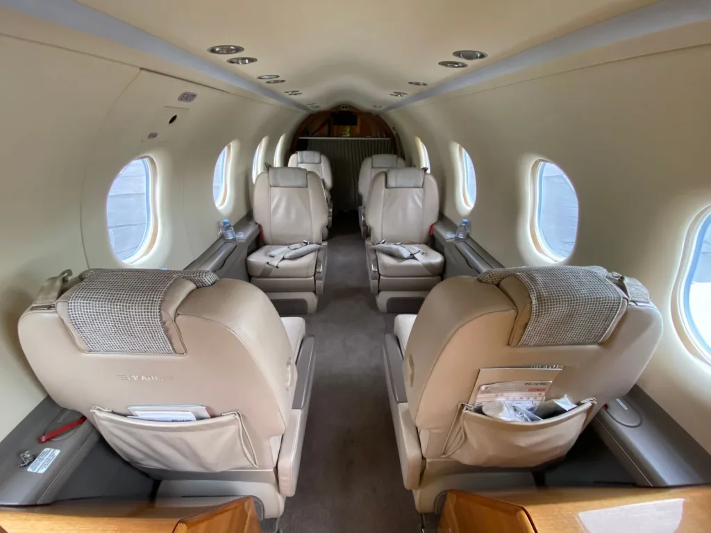 The beige leather interior cabin of an aircraft with four passenger seats visible, facing each other, from a slightly different angle.