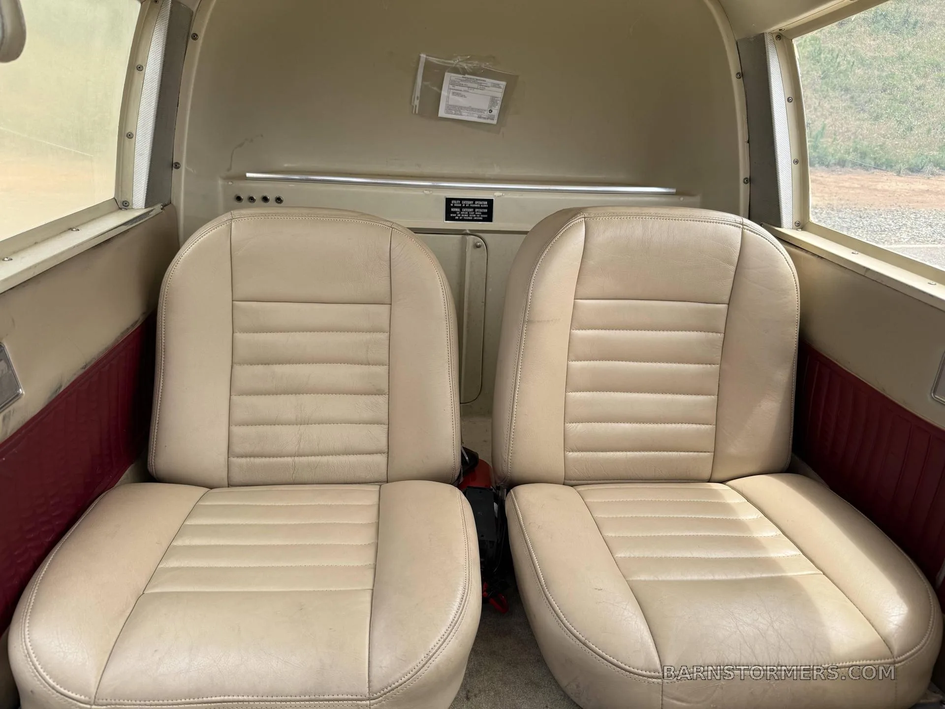 The rear two tan leather passenger seats in the cabin of a small aircraft.