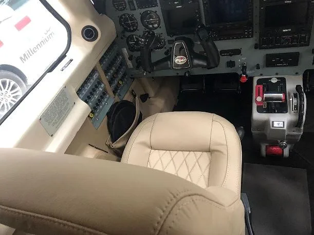 The tan leather pilot's seat and a partial view of the instrument panel and controls in the aircraft cockpit.