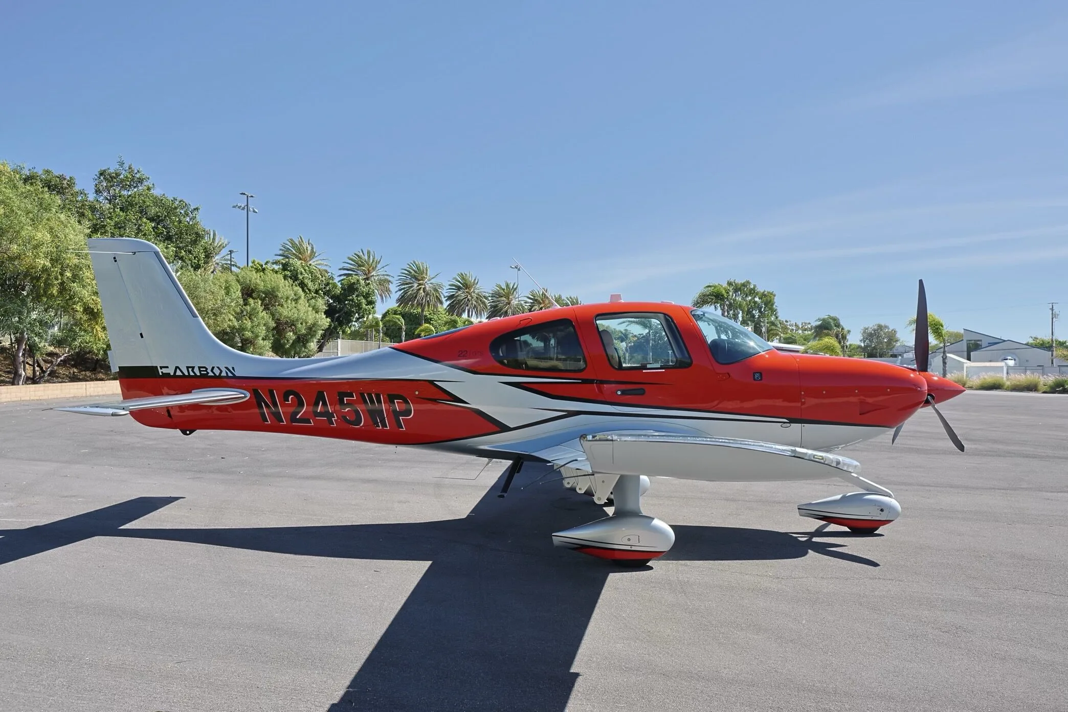 A red and silver Cirrus SR22 GTS aircraft, N245WP, parked on an tarmac under a clear sky.