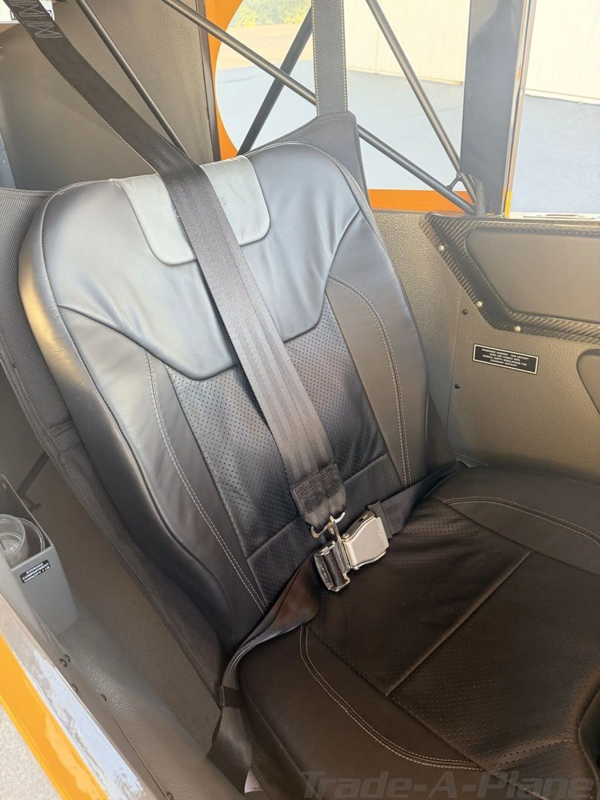 A black leather aircraft seat with a seatbelt is visible inside the cabin.