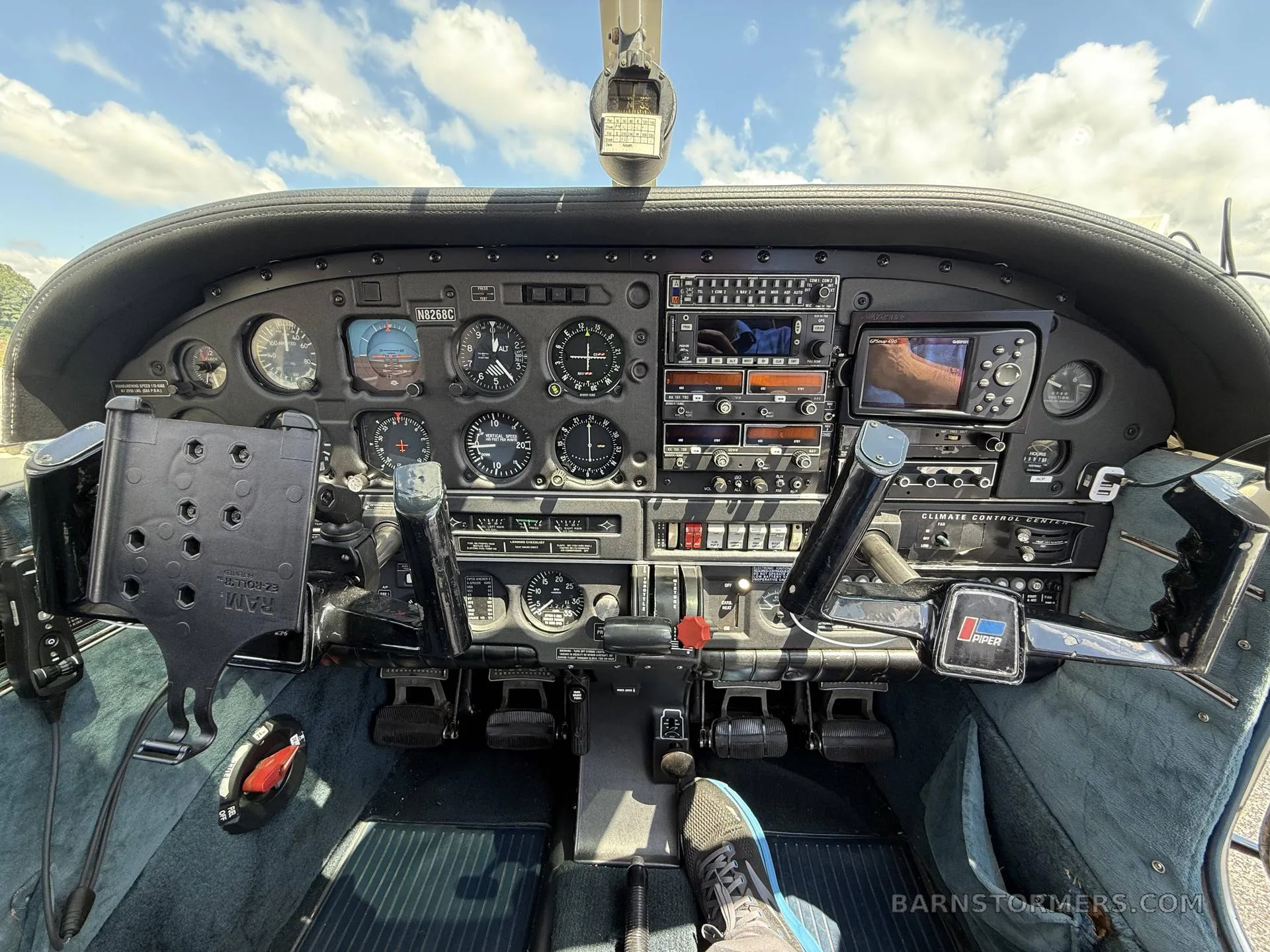 A detailed view of a Piper aircraft cockpit with analog gauges and modern avionics under a blue sky.
