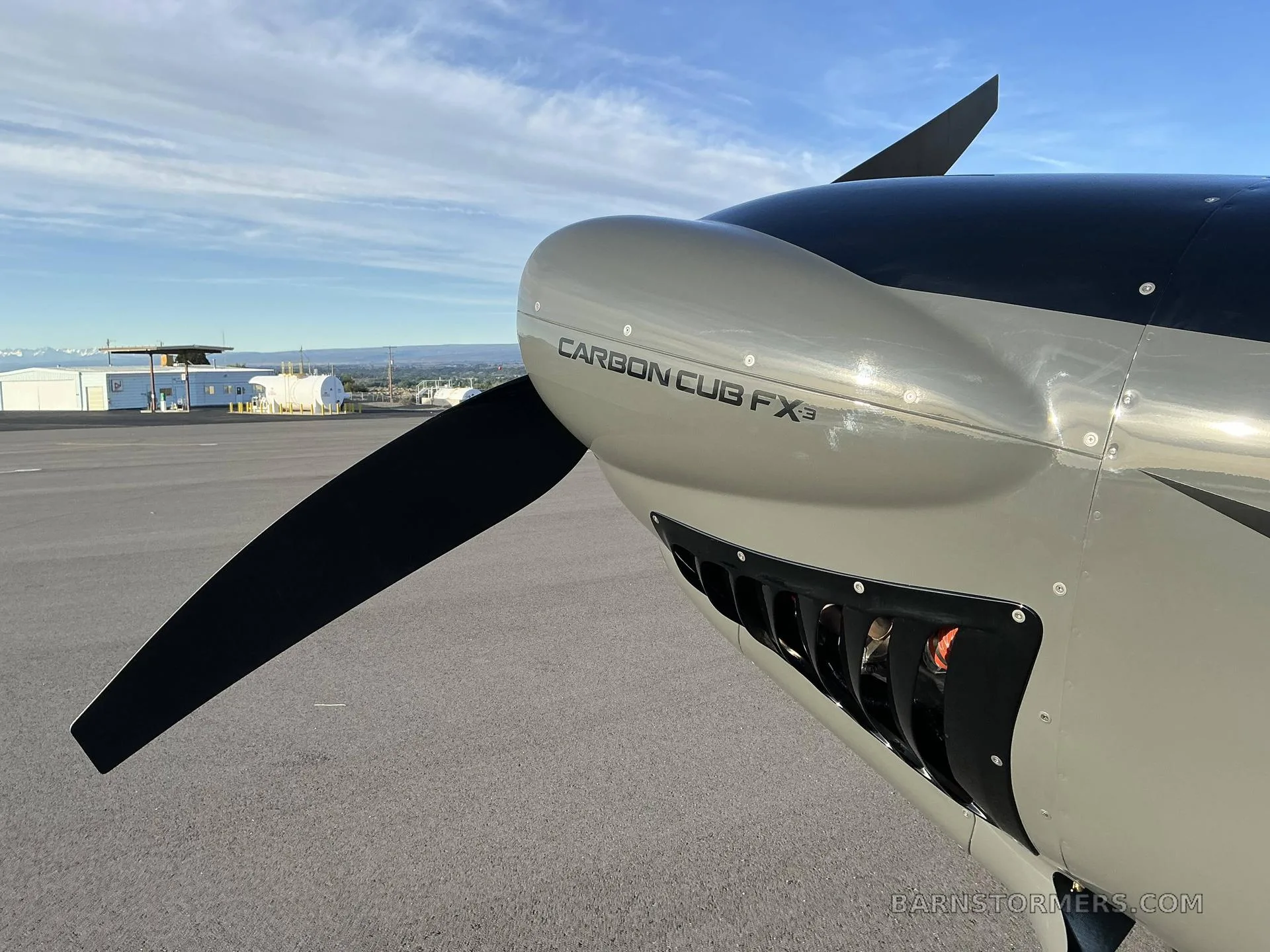 A close-up of the propeller and nose of a grey Carbon Cub FX3 aircraft, showing the engine cowling.
