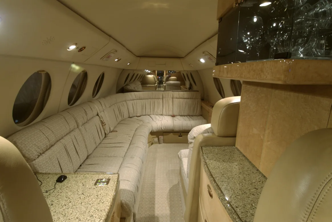 View of the aircraft's interior cabin with a long couch and cabinets.