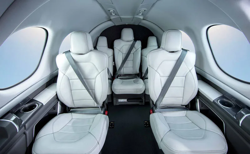 The interior of a jet with white leather seats and cup holders.