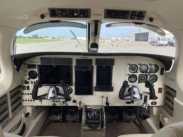 The aircraft cockpit features a modern glass panel display alongside traditional gauges and dual yokes.