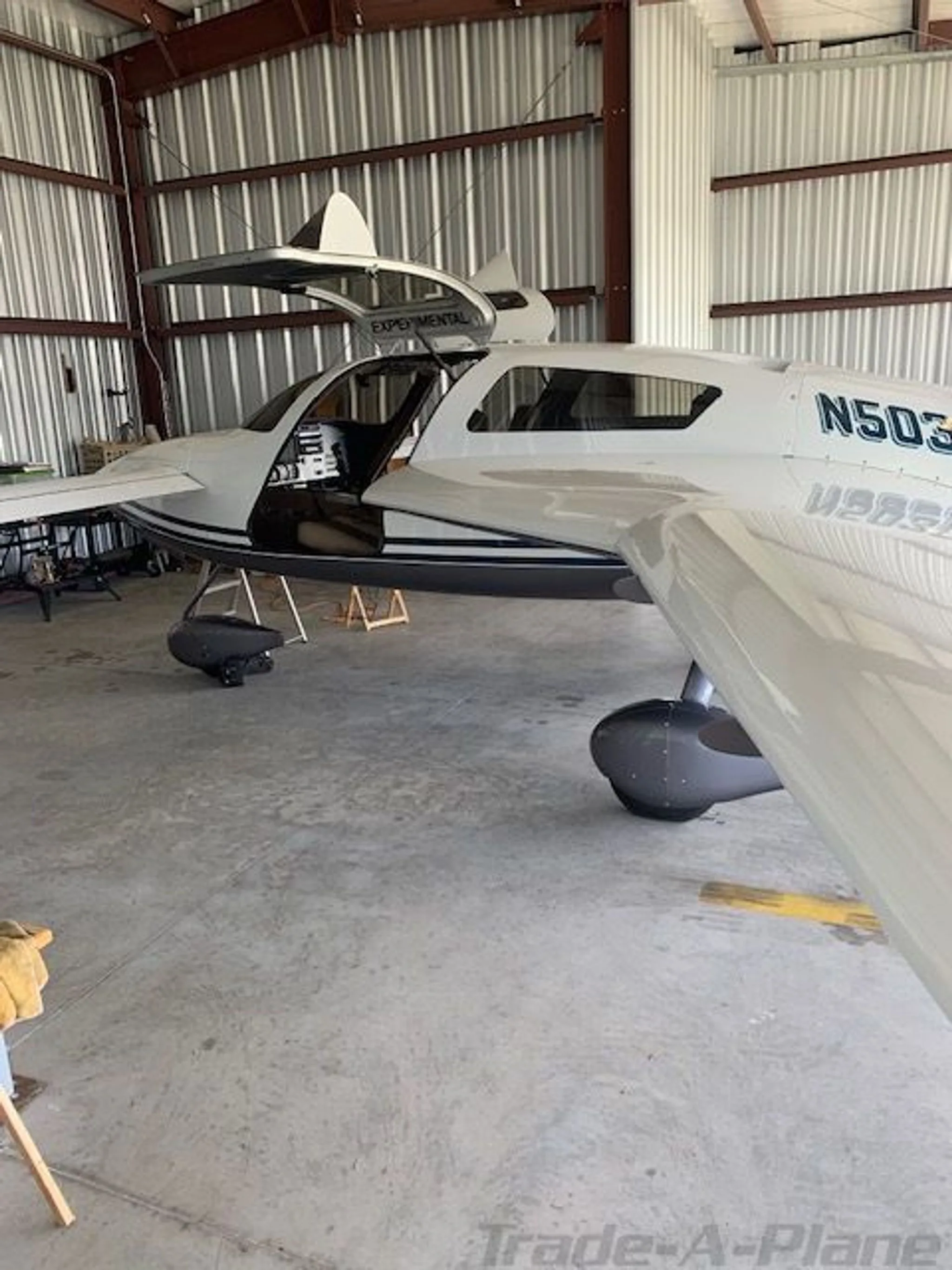 Side view of a white and dark grey Velocity aircraft with its gull-wing doors open, showing the N503PV registration.
