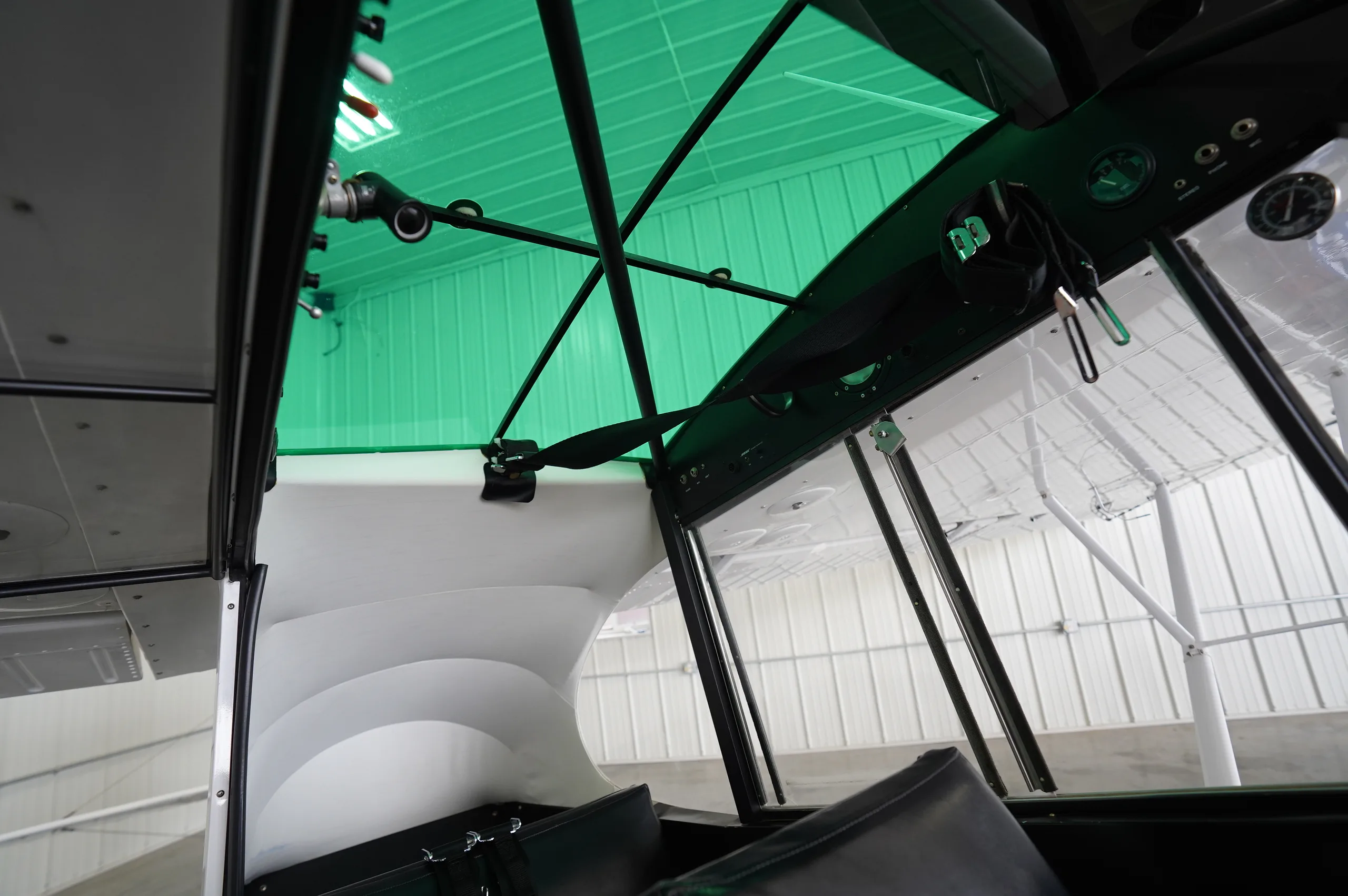 An interior view looking up at the green-tinted skylight and structural elements of a Piper Cub aircraft.