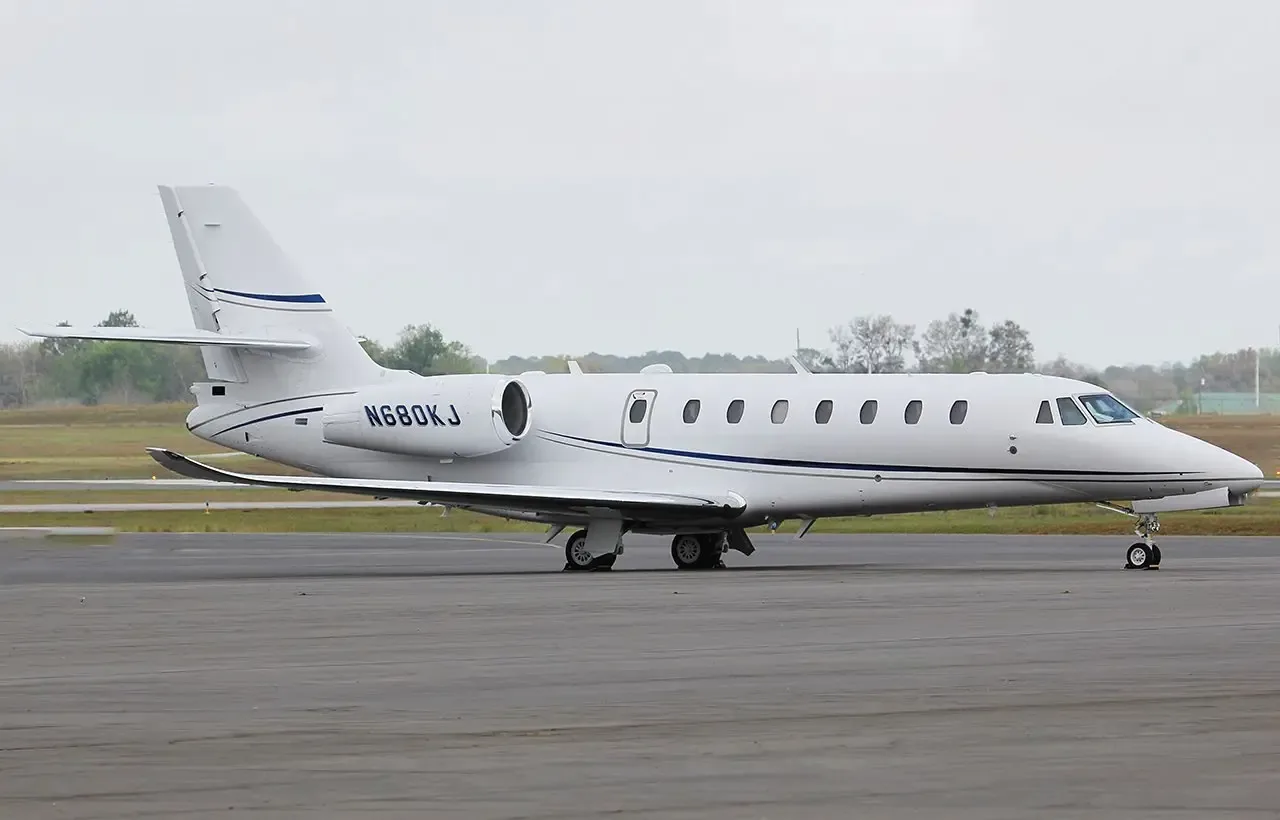 A white Cessna Citation Latitude business jet with registration N680KJ parked on a tarmac under an overcast sky.