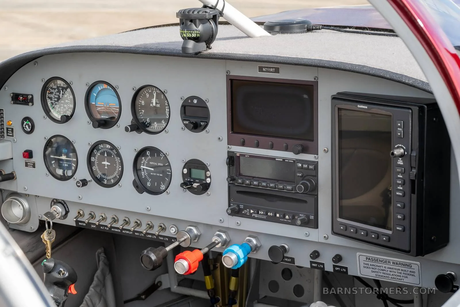 The cockpit instrument panel of the N711RT experimental aircraft, showing analog gauges and two digital displays.