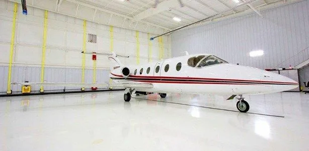 A white Learjet 25 is parked inside a hangar.