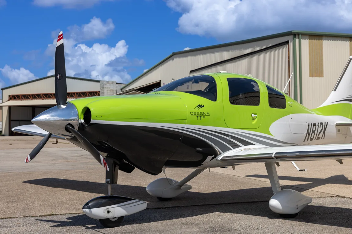 A close-up view of the front and side of a lime green, white, and black Cessna TTX aircraft with registration N812K.