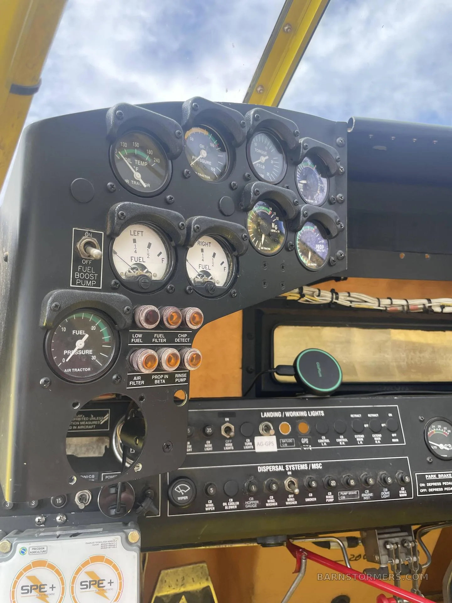 A close-up view of the instrument panel in a yellow agricultural aircraft, displaying various gauges, switches, and controls.