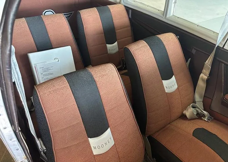 The brown and black fabric interior seats of a Mooney M20 aircraft cabin.