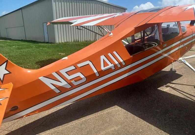 A close-up view of the tail section of the orange N57411 aircraft, showing the registration number and white star decals.