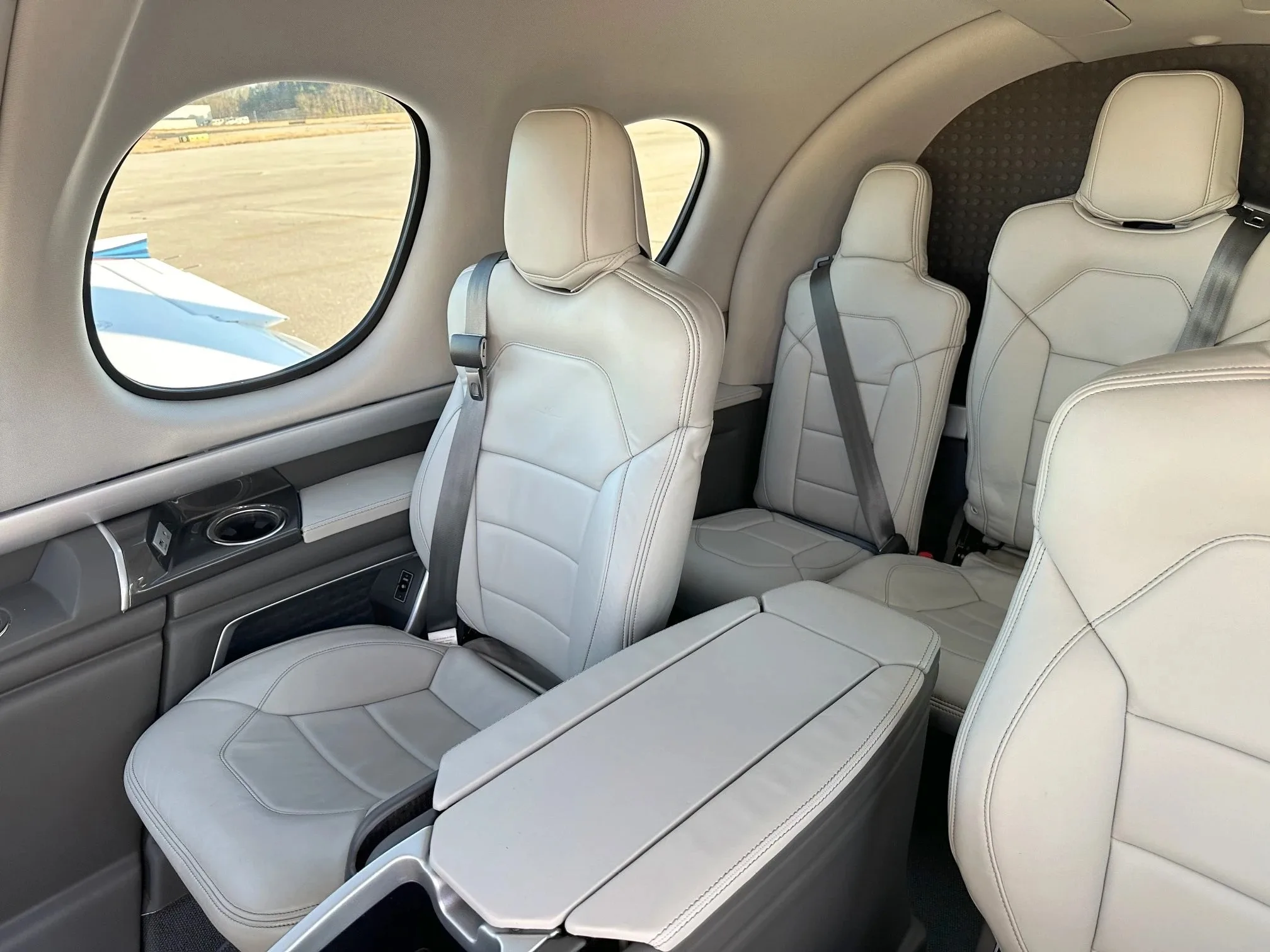 The light gray leather passenger cabin of a Cirrus Vision Jet, showing three seats and a center console.