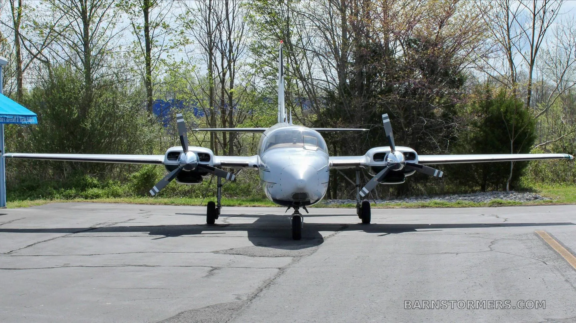 A head-on view of a white Piper Aerostar twin-engine aircraft with black propellers, parked on an asphalt ramp.