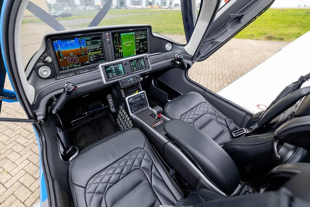 The modern cockpit of a Cirrus SR22T GTS, featuring large digital displays and black leather seats with diamond stitching.