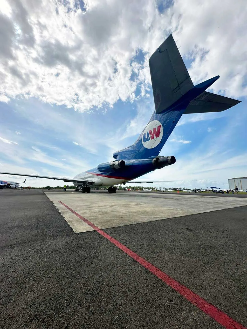 The tail section of a UniWorld Air Cargo Boeing 727-200F on the tarmac under a cloudy sky.