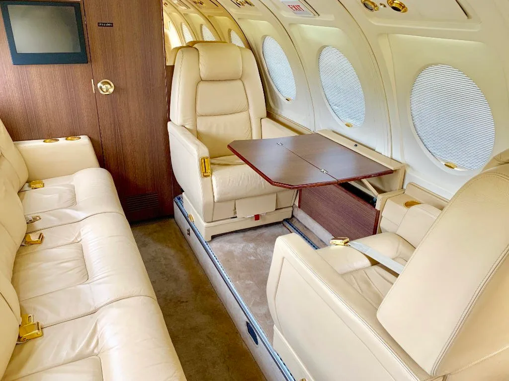 A view of the aircraft's interior with cream-colored leather seats and a table.