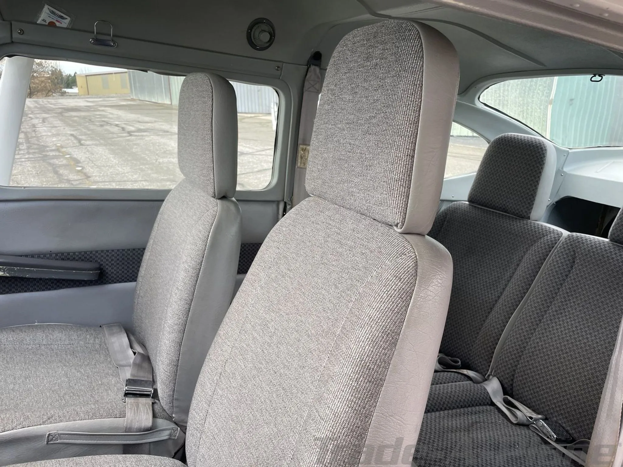 The gray fabric interior cabin seats of a Cessna 182 aircraft, viewed from the rear.