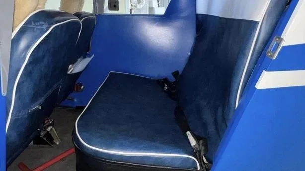 Close-up view of the blue rear seats with white piping in the aircraft cabin.