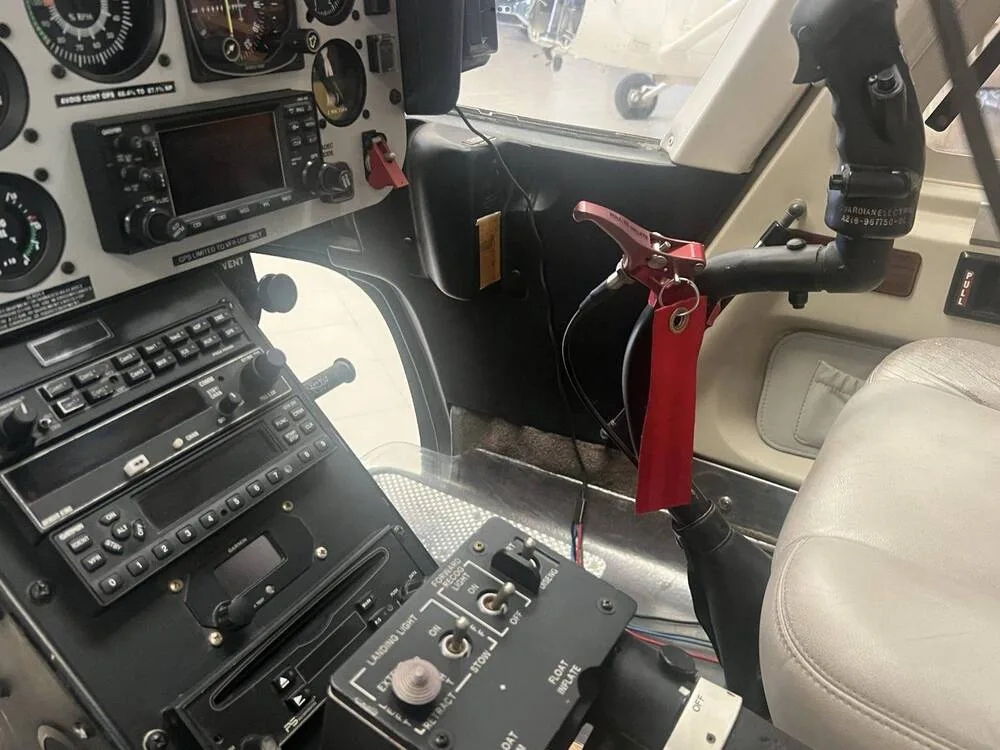 The lower instrument panel, radio stack, and collective control with a red handle in a helicopter cockpit.
