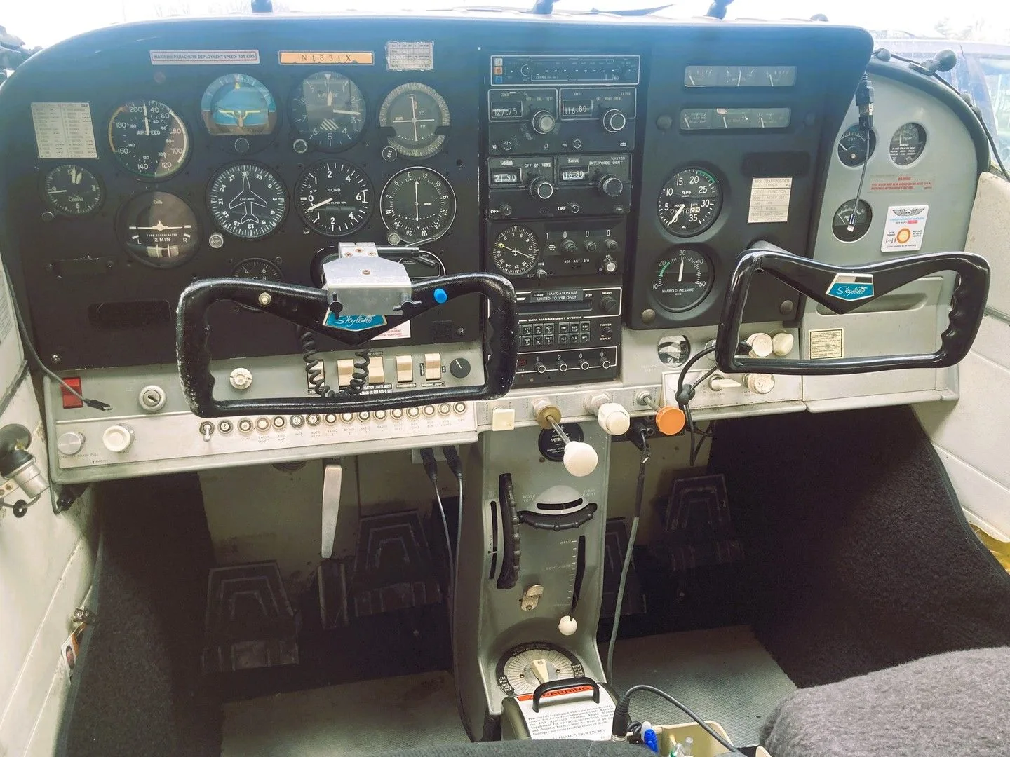 A detailed view of the cockpit of a Cessna 182, showing the instrument panel, yokes, and center console.