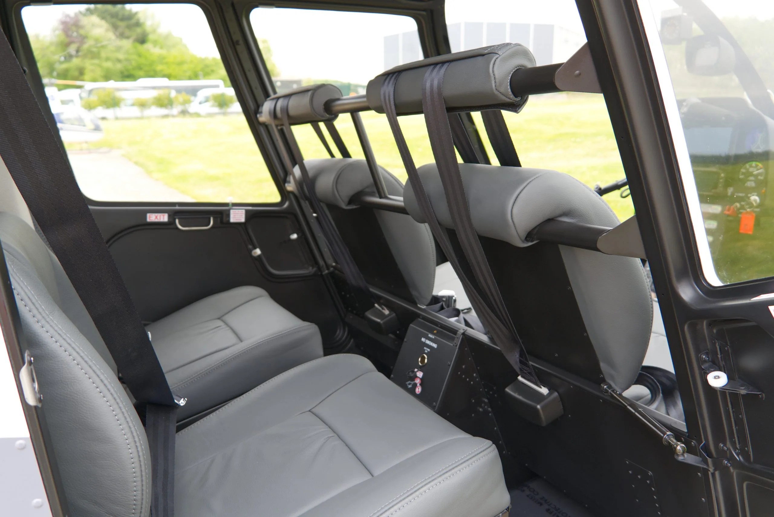 The gray leather passenger seats and interior of a helicopter cabin, viewed from the side.