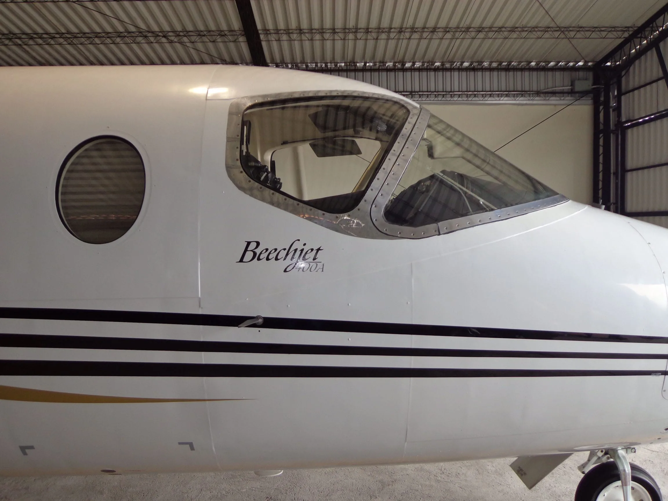 A close-up of the cockpit and front fuselage of a white Beechjet 400A, showing the 'Beechjet 400A' text inside a hangar.