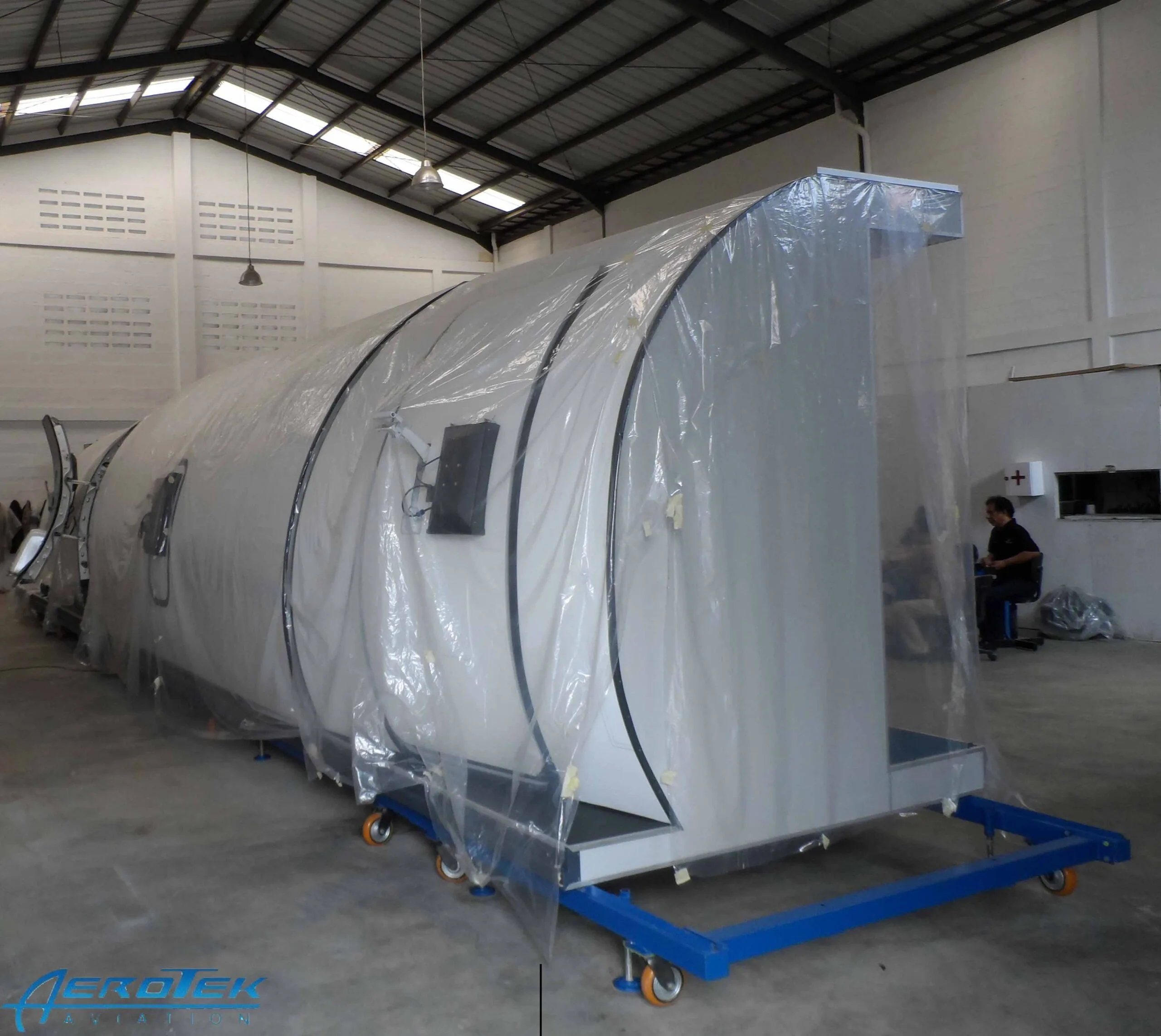 A training mock-up of an aircraft cabin with blue seats and illuminated windows.