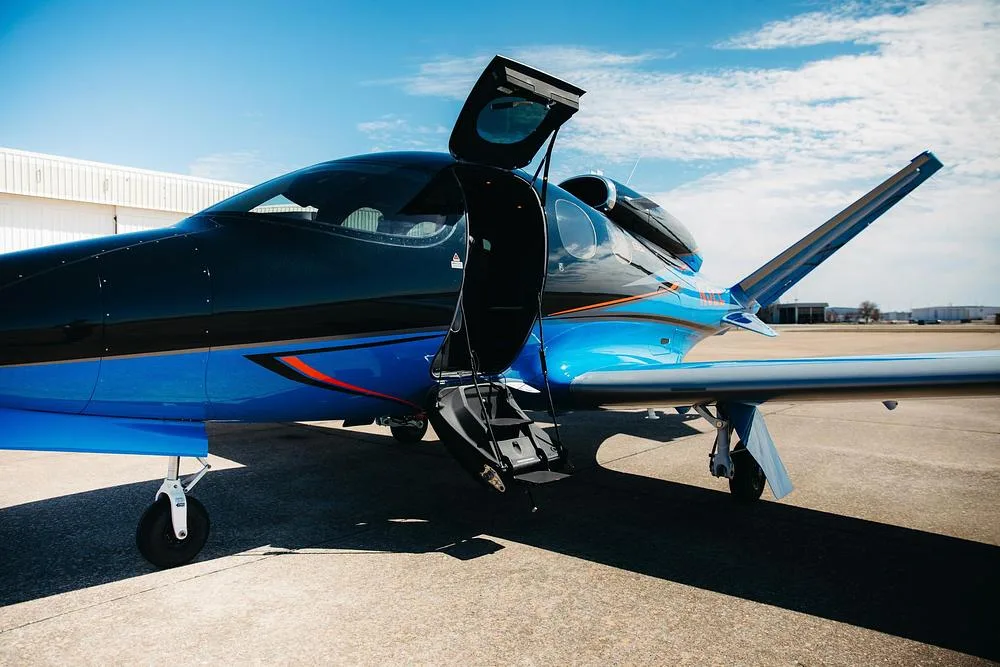 A close-up view of the blue and black Cirrus Vision Jet with its entry door and steps open.