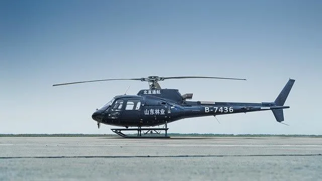 A dark blue Airbus H125/AS350 helicopter with registration B-7436 is parked on an asphalt tarmac under a clear sky.