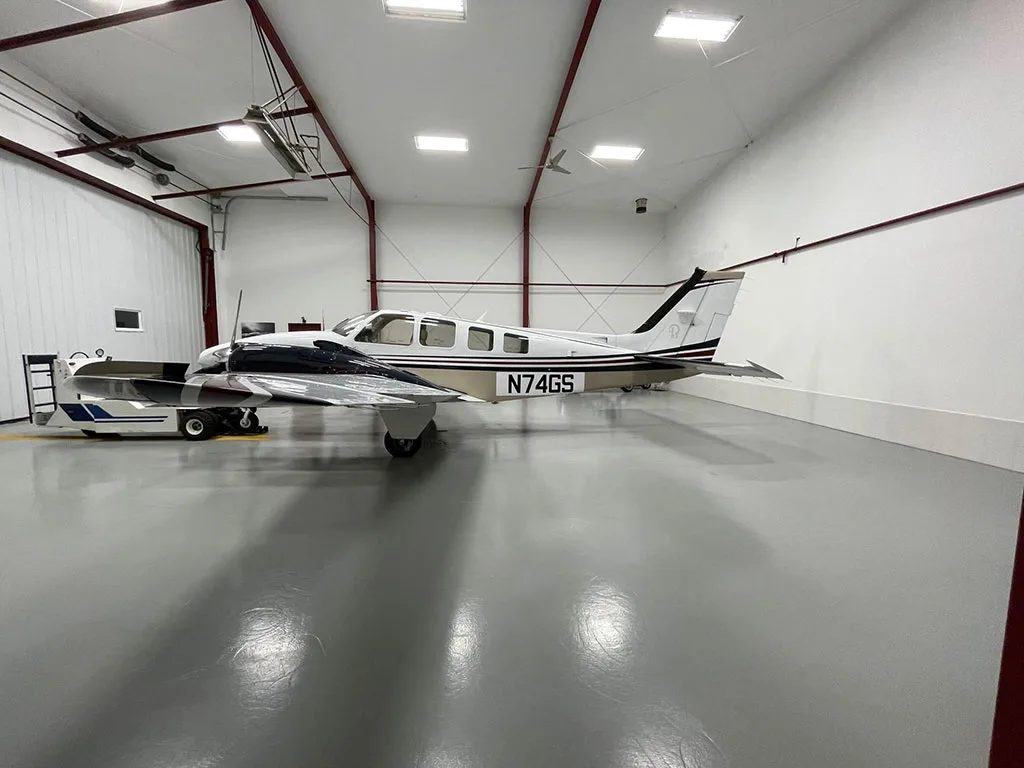 A wide side view of the white and tan twin-engine aircraft N74GS with dark blue accents, parked in a hangar.