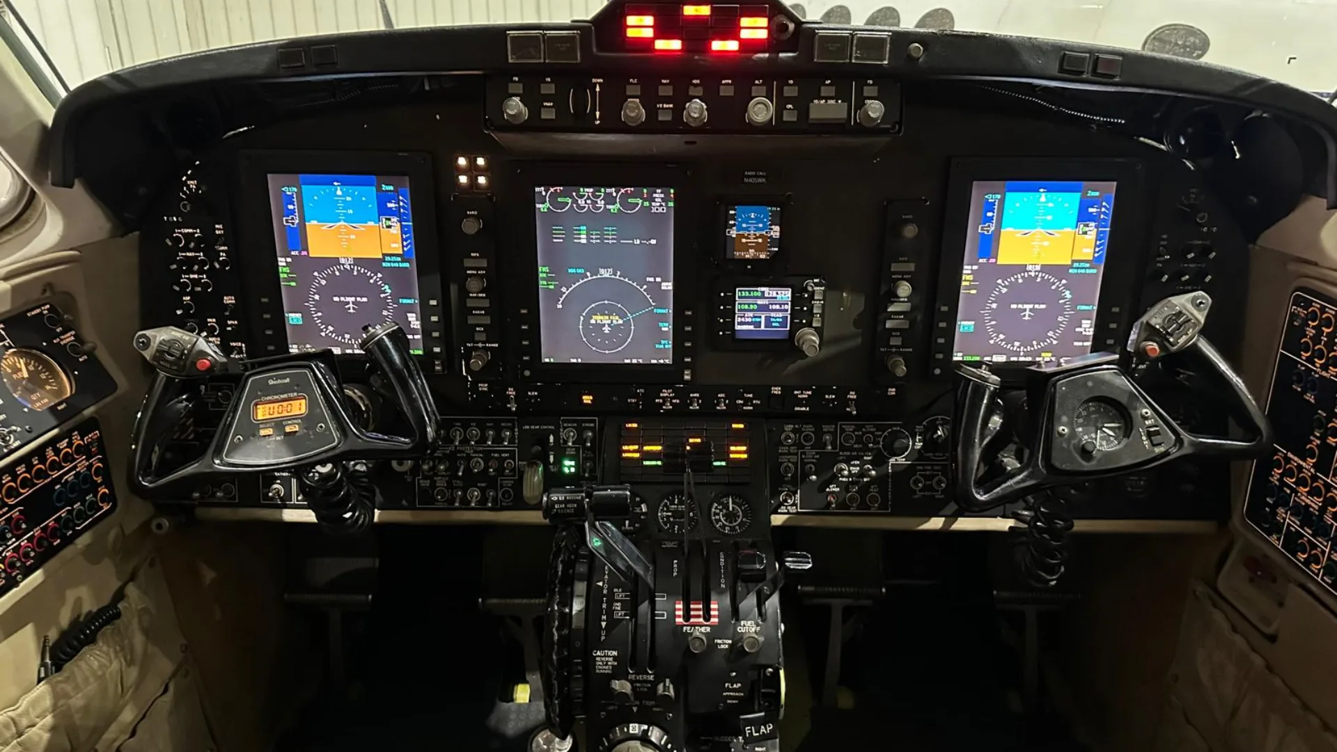 The modern cockpit of an aircraft, featuring multiple digital displays and control yokes.