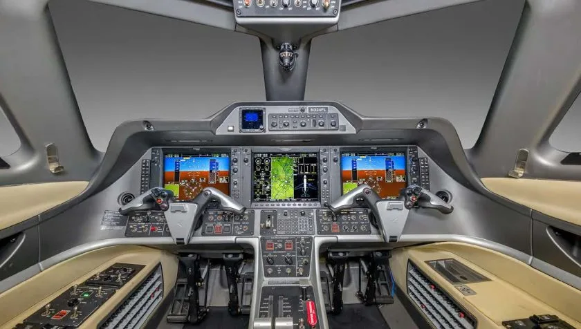 The cockpit of an Embraer Phenom 300 private jet, featuring a modern glass panel display with multiple screens.