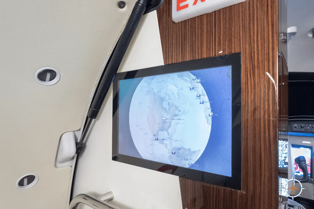 An in-flight entertainment screen displaying a global map, mounted on the aircraft's interior wall.