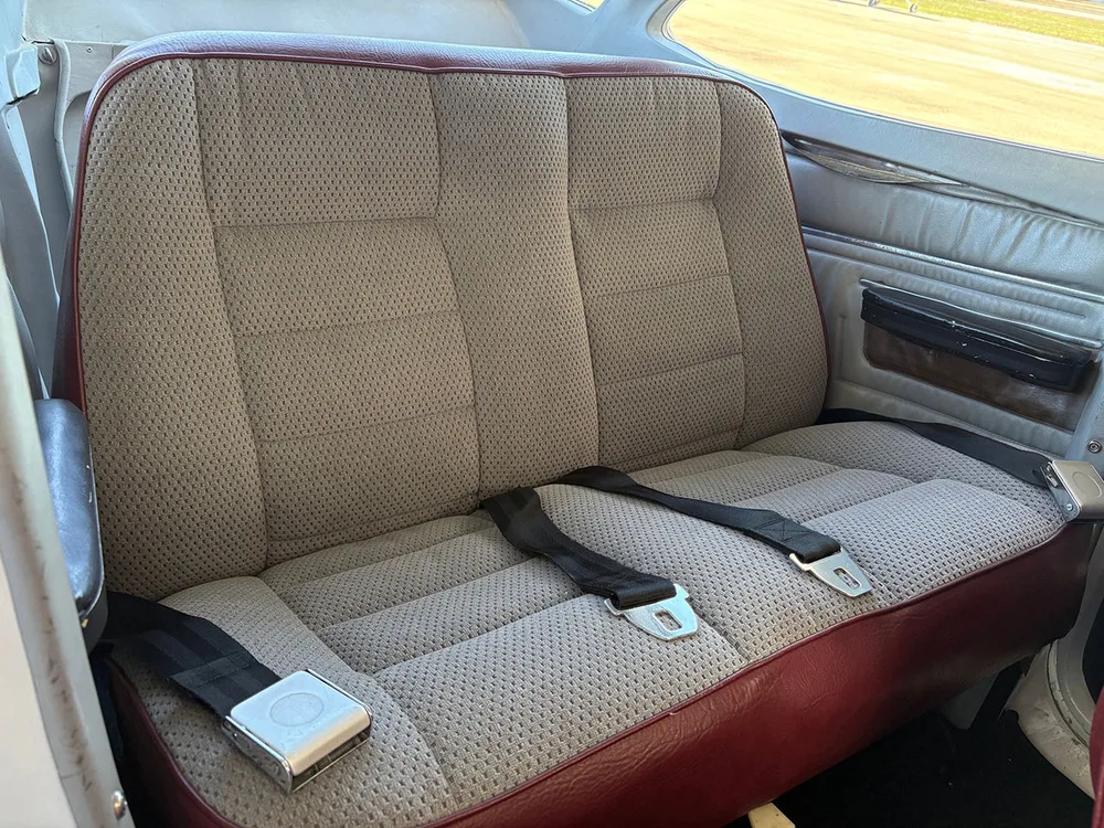 The rear two seats of the aircraft, upholstered in grey fabric with red trim.