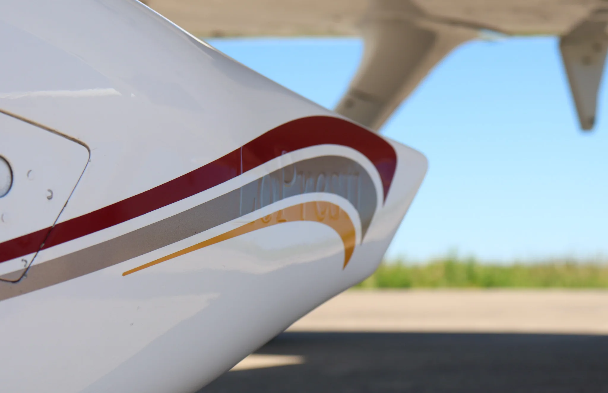 Close-up of the red, grey, and gold stripe detail on the side of a white Cirrus SR22 fuselage.