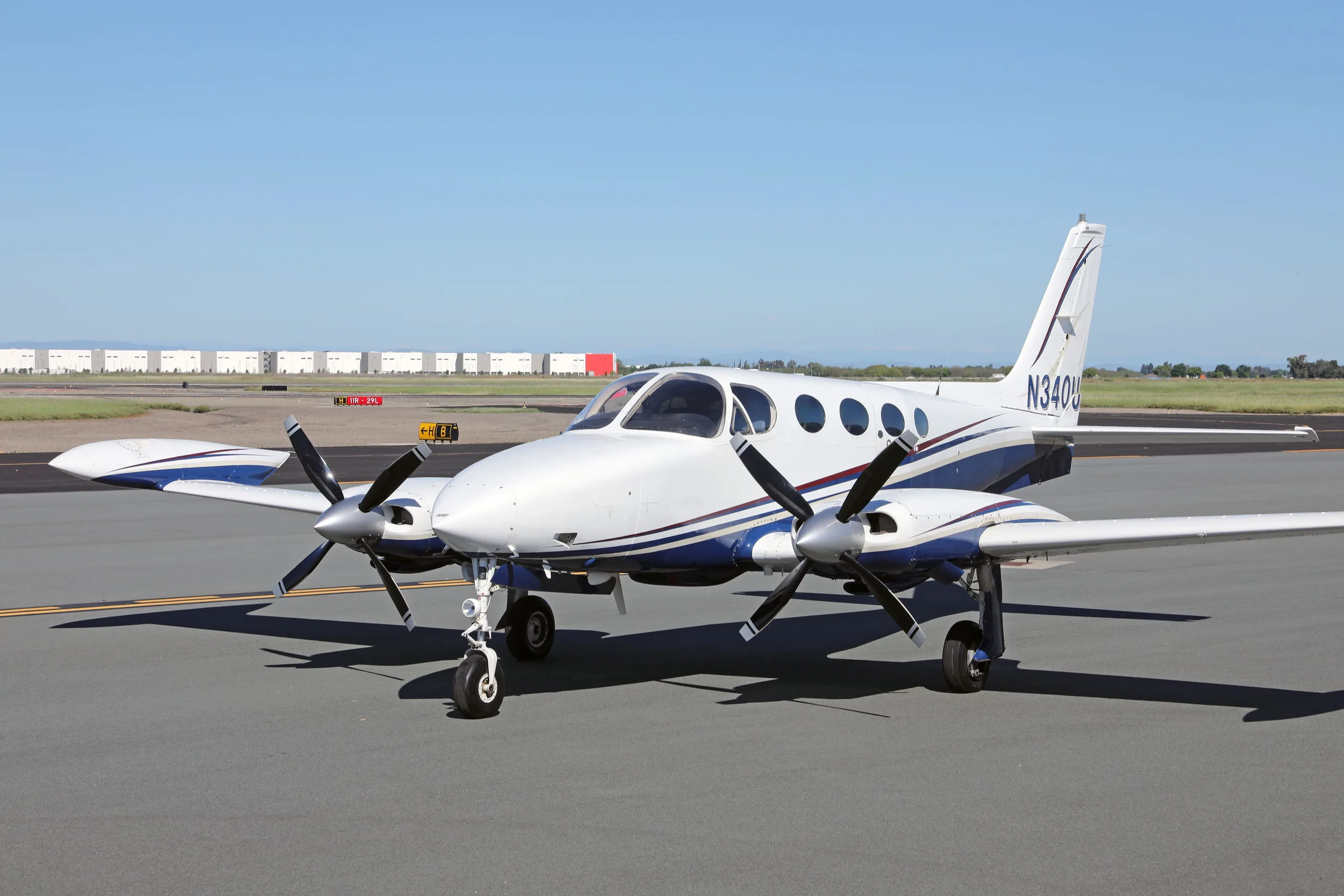 A three-quarter front view of a white and blue Cessna 340 twin-engine aircraft with registration N340U on an airfield.