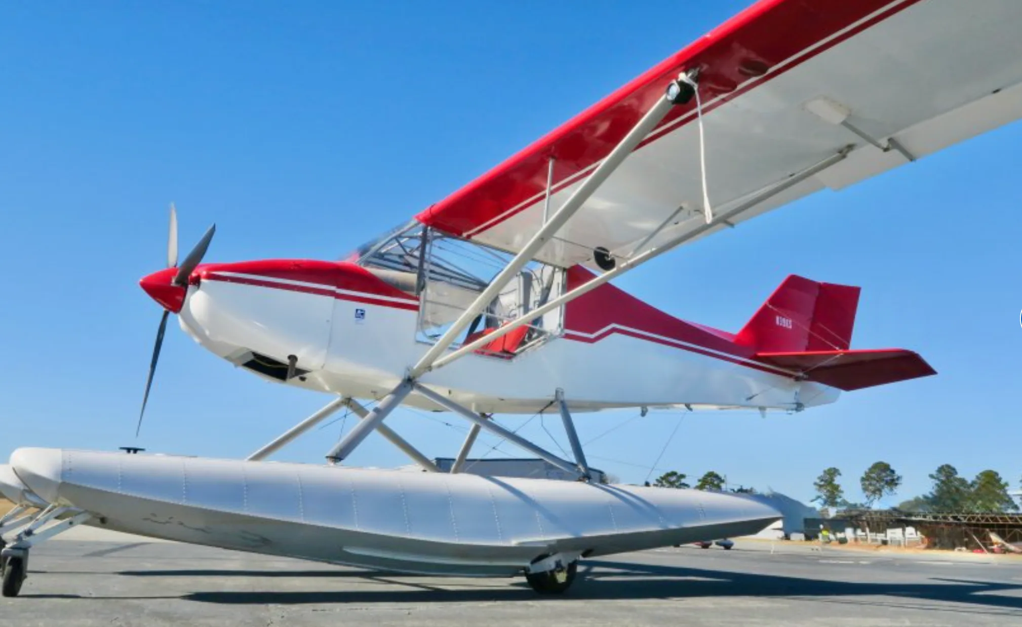 A close-up front-side view of the red and white N39KS floatplane showing its propeller and floats.