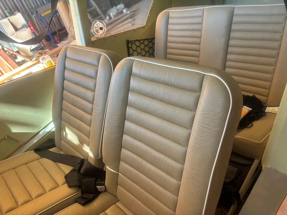 The light brown pleated seats with white piping are visible inside the aircraft cabin.