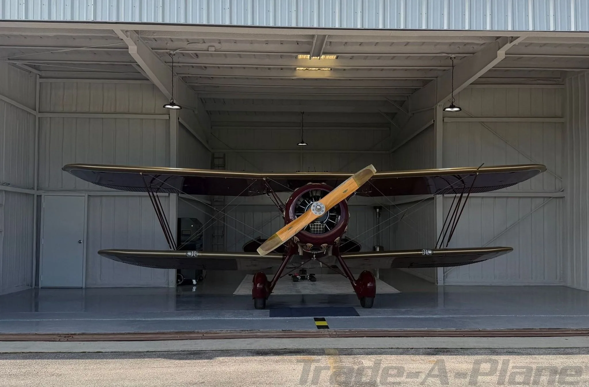 A frontal view of a WACO YMF-5C in a hangar.