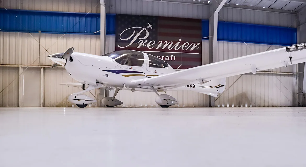 A low-angle front-left view of a white Diamond DA40 Star aircraft, registration N208DS, in a hangar.