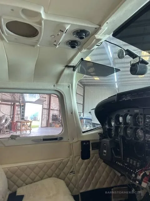 A side view of the aircraft's cockpit shows the instrument panel, quilted side panel, and overhead controls.