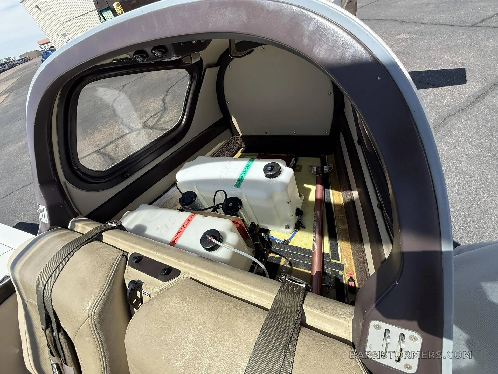 An interior view of the aircraft's cargo area, showing two white auxiliary fuel tanks secured behind the seats.