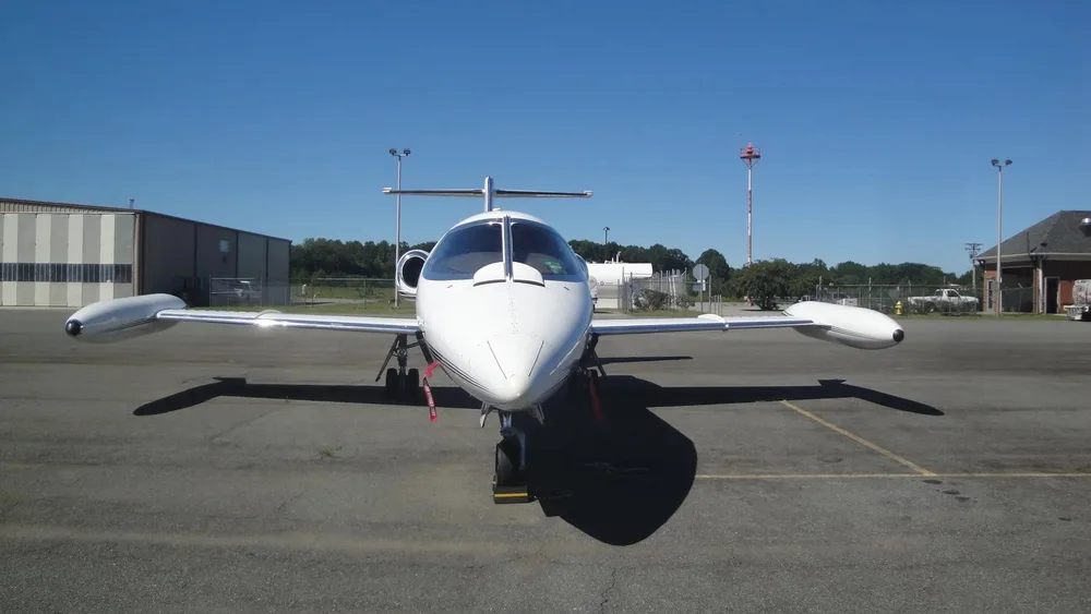 A white Learjet N251TS is seen from the front, parked on an airport tarmac.