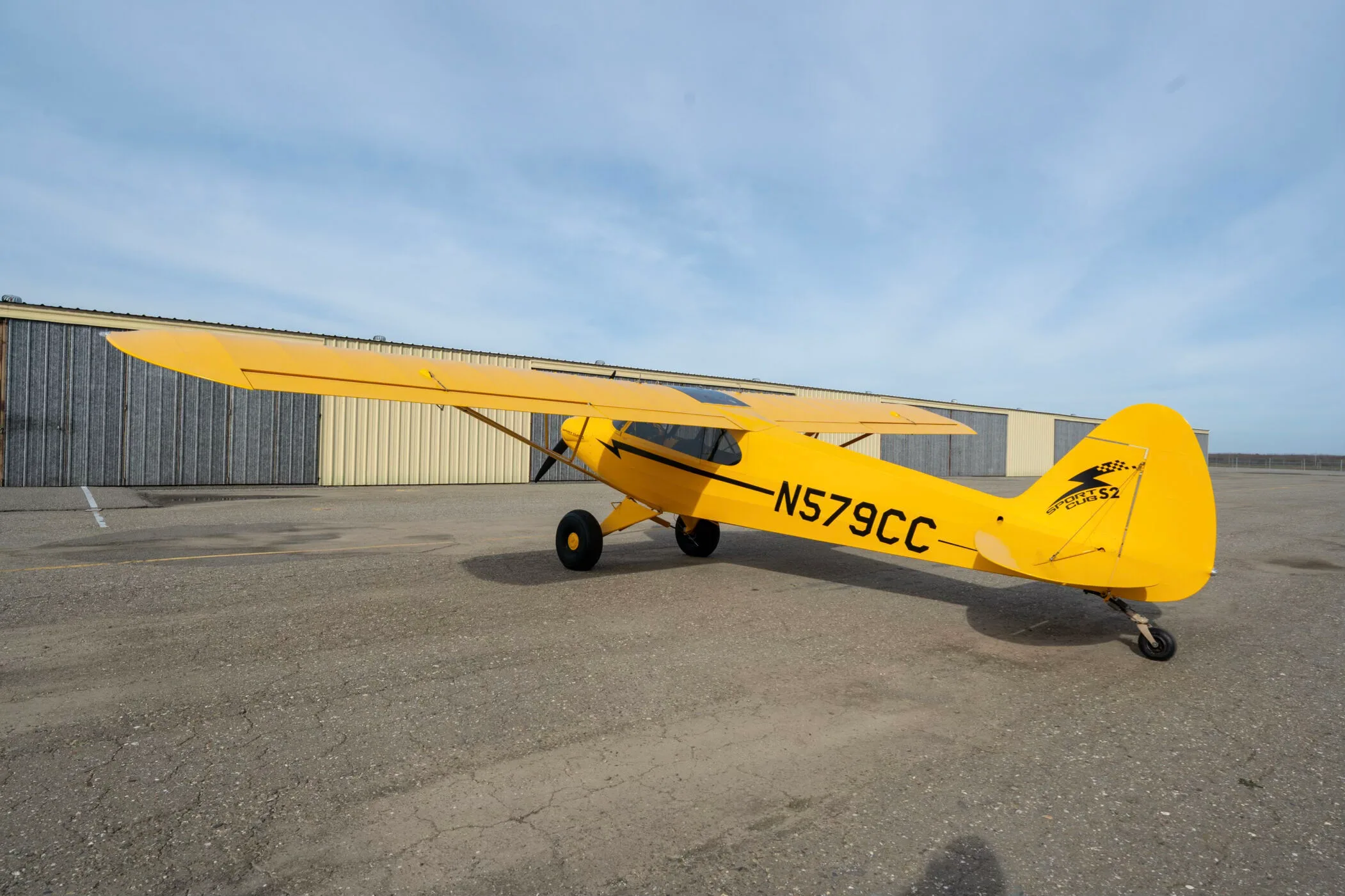 A rear-left view of the yellow CubCrafters Sport Cub S2 aircraft N579CC parked on an airfield.